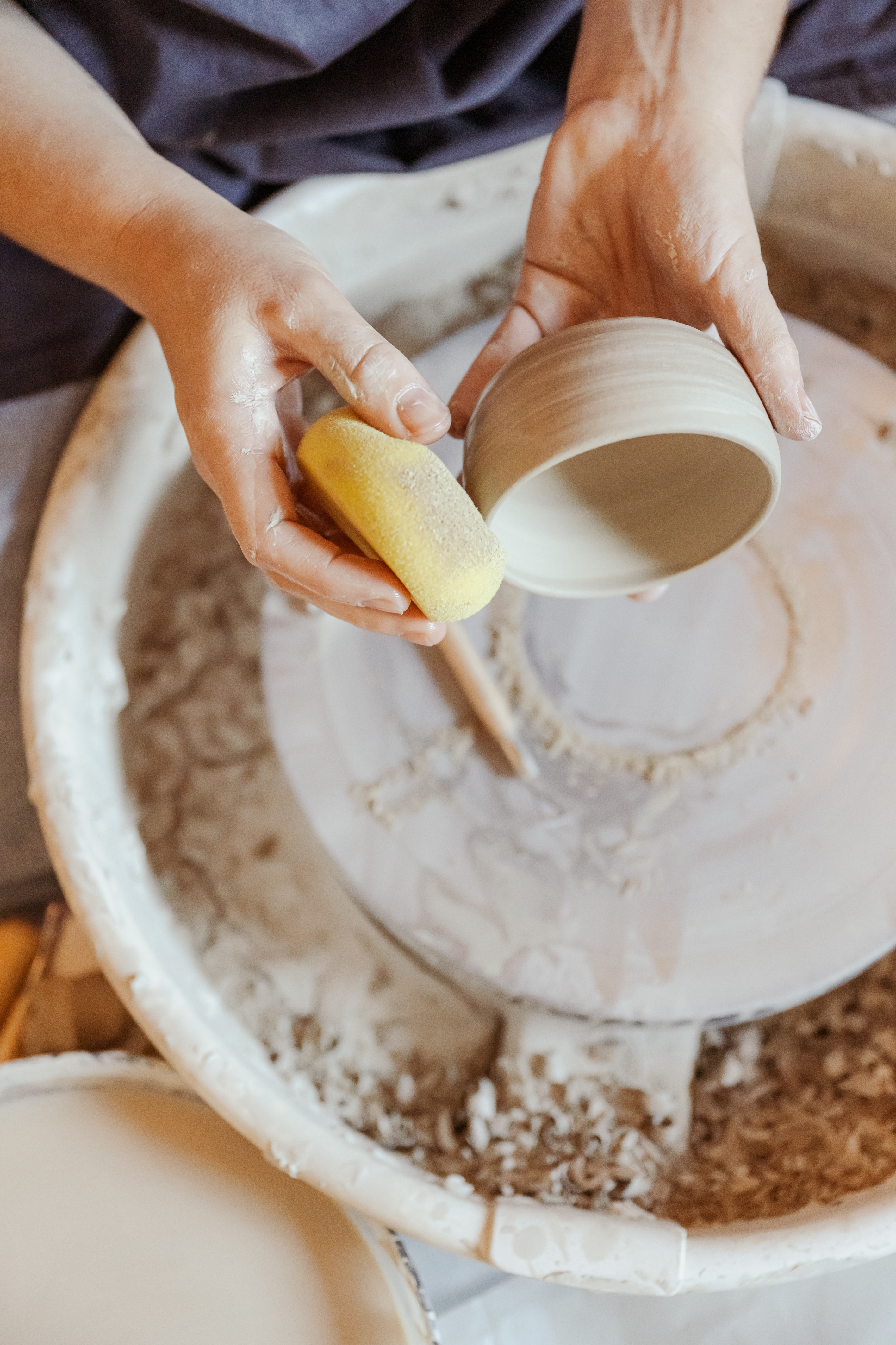 Adulte façonnant une tasse au tour de potier dans un atelier en Alsace