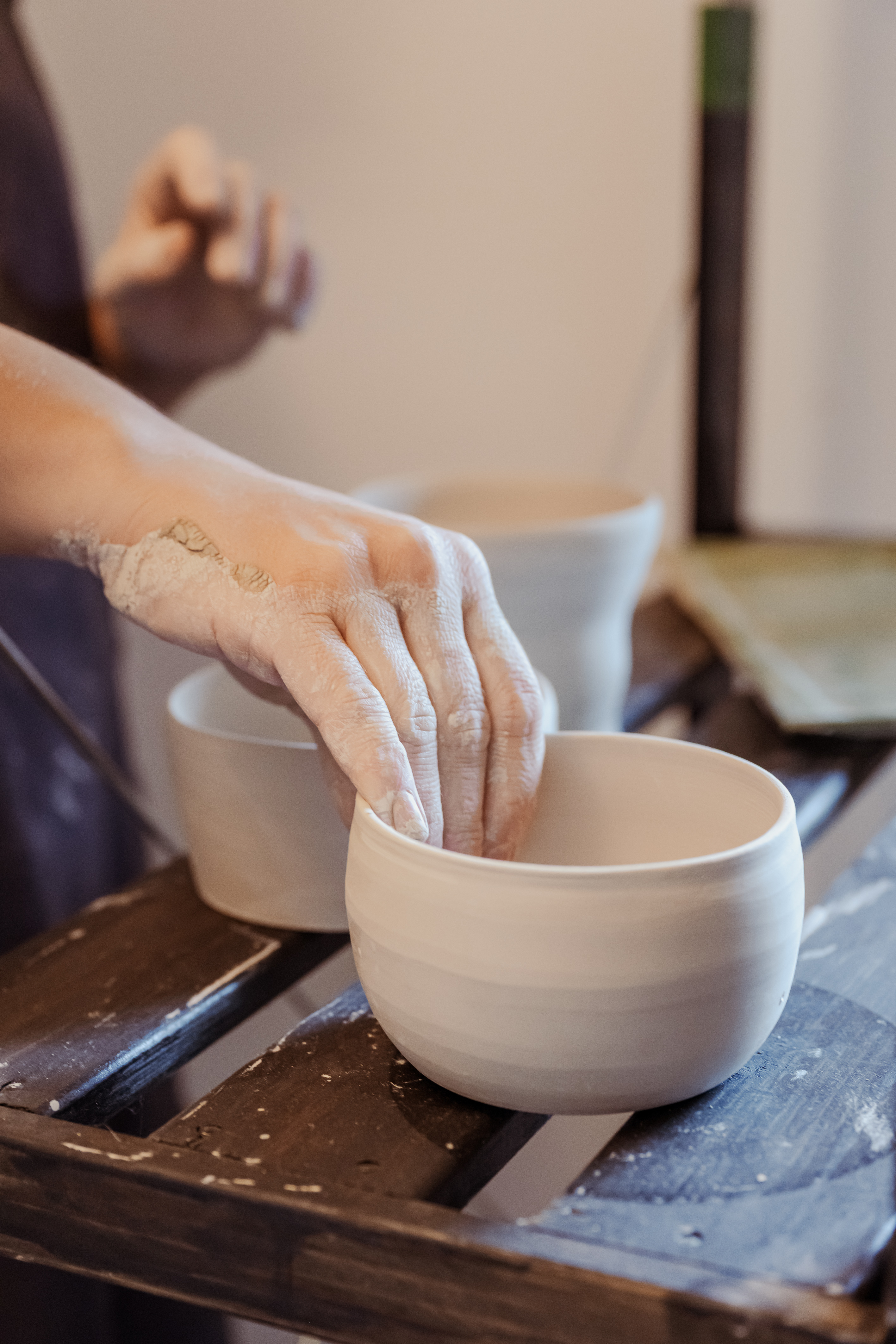 Participant adulte modelant un bol en argile lors d’un atelier de céramique